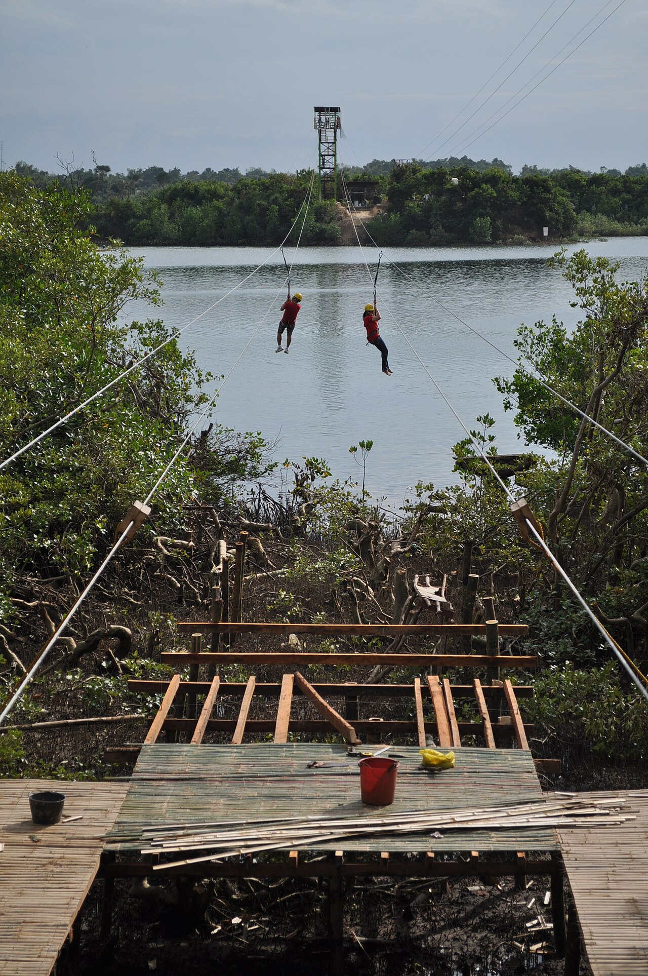 Two people ziplining side by side over the water
